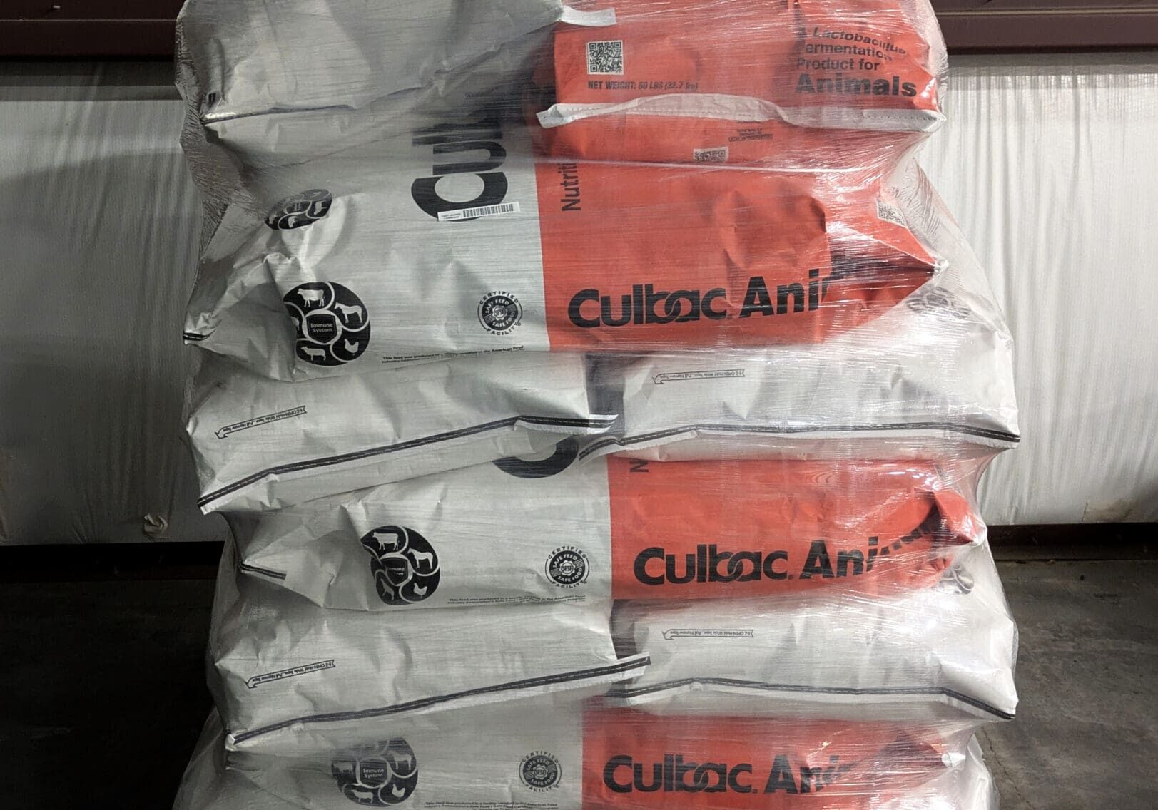 Stacked bags of cement on a wooden pallet, half labeled red and half gray.