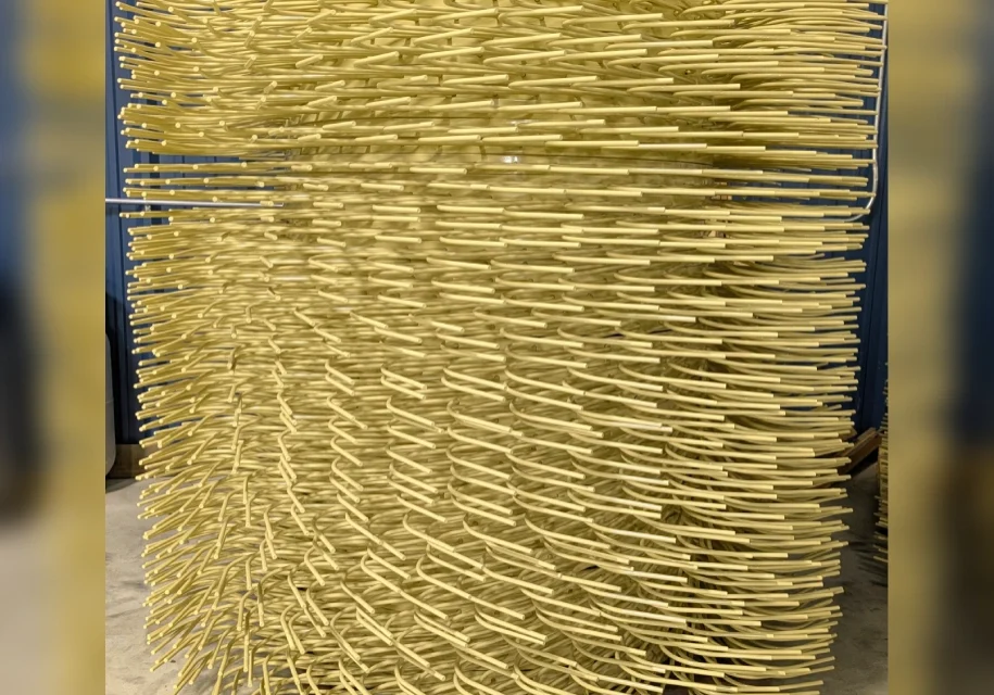 Art installation with numerous wooden sticks arranged densely in a curved formation.